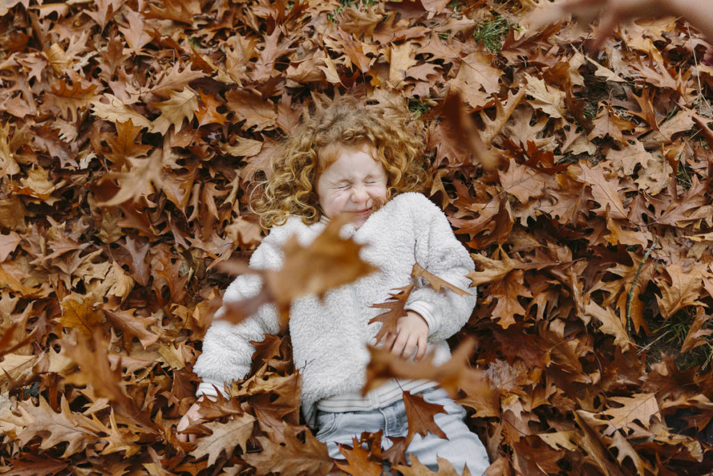 ein Kind liegt im roten Herbstlaub | Foto: Hanna Witte