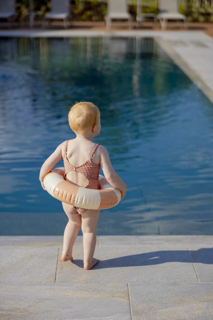 ein Mädchen läuft mit einem Schwimmreifen um die Hüften am Rand eines Pools | Foto: Hanna Witte