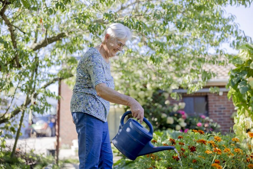 eine Landwirtin gießt ihr Pflanzenbeet mit einer blauen Gießkanne | Foto: Hanna Witte